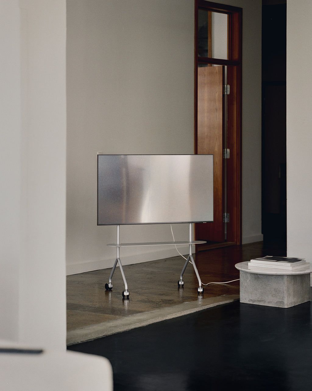 Moon Light in Cloudy Silver rolling TV stand with wheels holding a flat-screen in a minimal concrete-floor living room